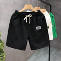 Men's solid colour polyester sports shorts on a hanger, showing elastic waistband and casual cut.