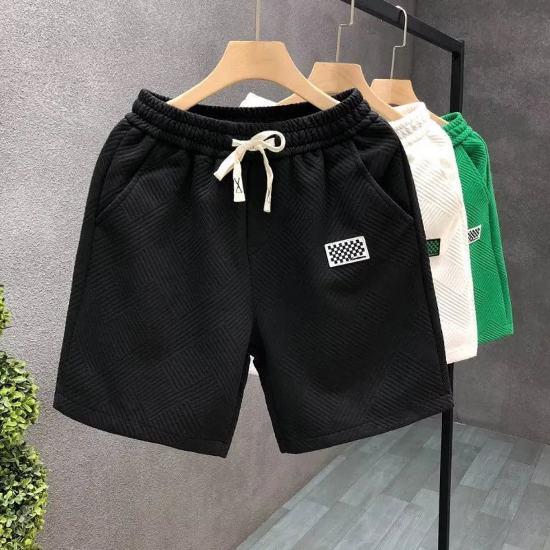 Men's solid colour polyester sports shorts on a hanger, showing elastic waistband and casual cut.