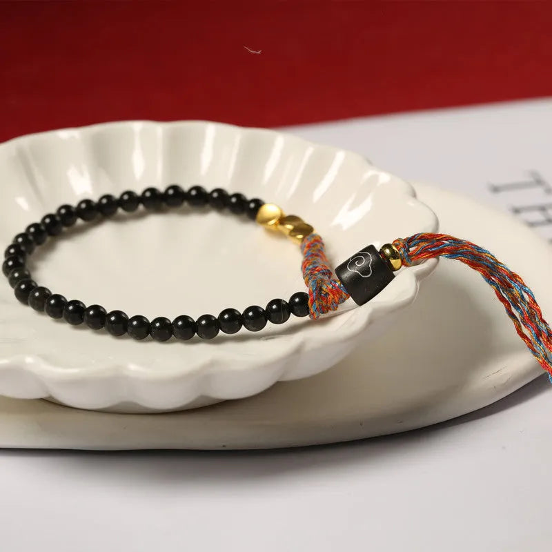 Hand-woven obsidian carrying strap bracelet showing textured surface and dark colour