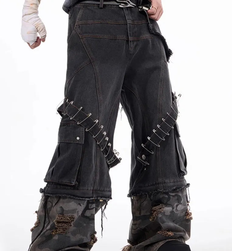 Grey men's jeans with camouflage pattern splicing and silver pin and black ribbon detailing on the legs.