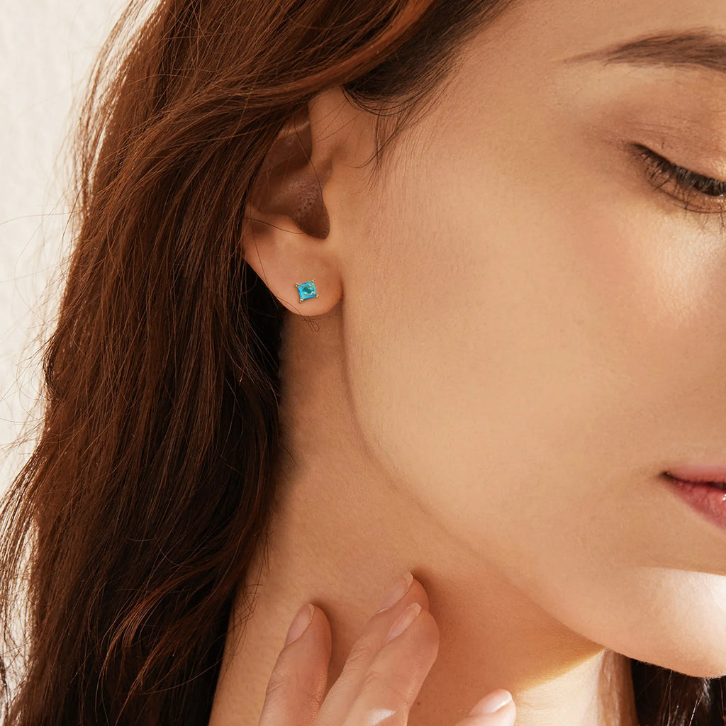 Gold-plated drop-shaped earrings with zircon accents in candy colours on white background
