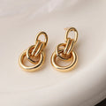 Geometric gold-coloured copper earrings with irregular design elements and high-profile construction
