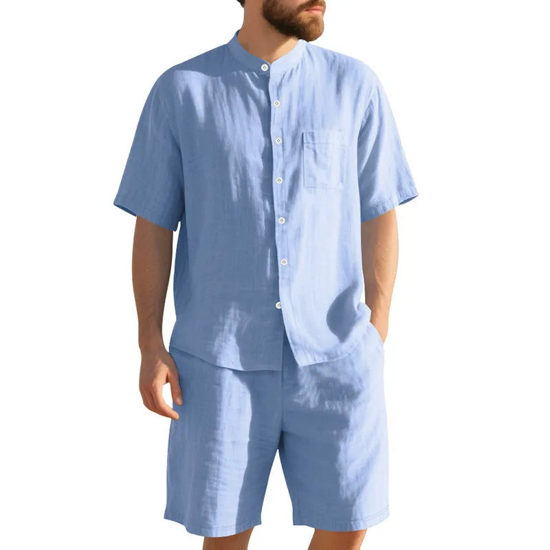Man wearing a light blue linen blend Henry collar short sleeve suit top with matching shorts.