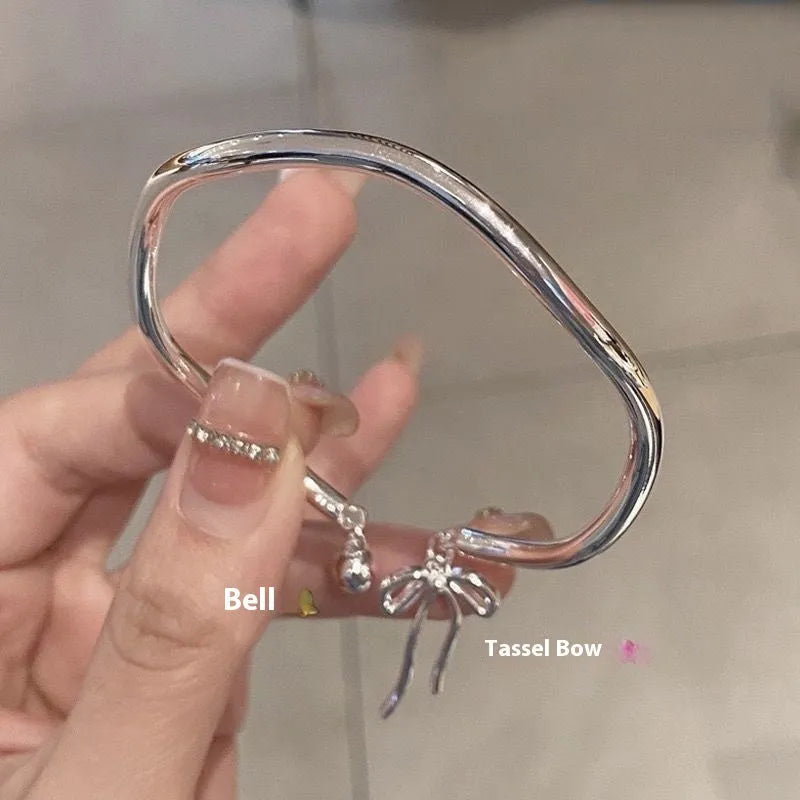 Silver adjustable bracelet with bow charm featuring bell opening detail