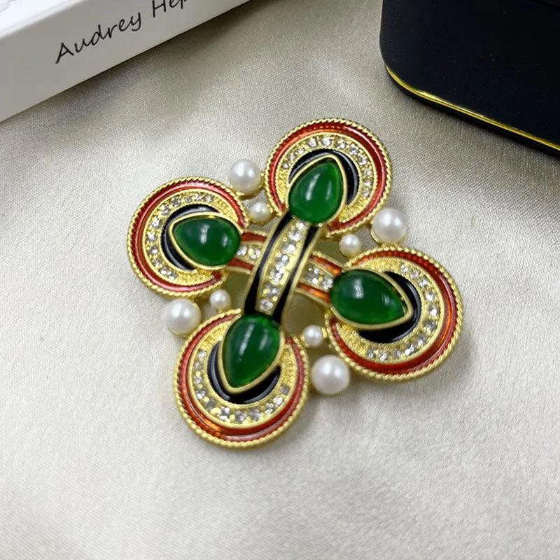 Vintage zinc alloy baroque cross brooch with crystal details on a dark fabric background.