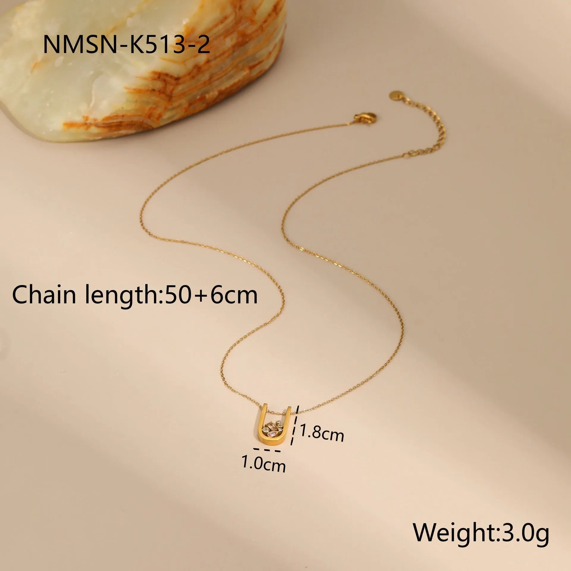 Geometric gold plated zircon necklace, ring, and earrings set on a plain background