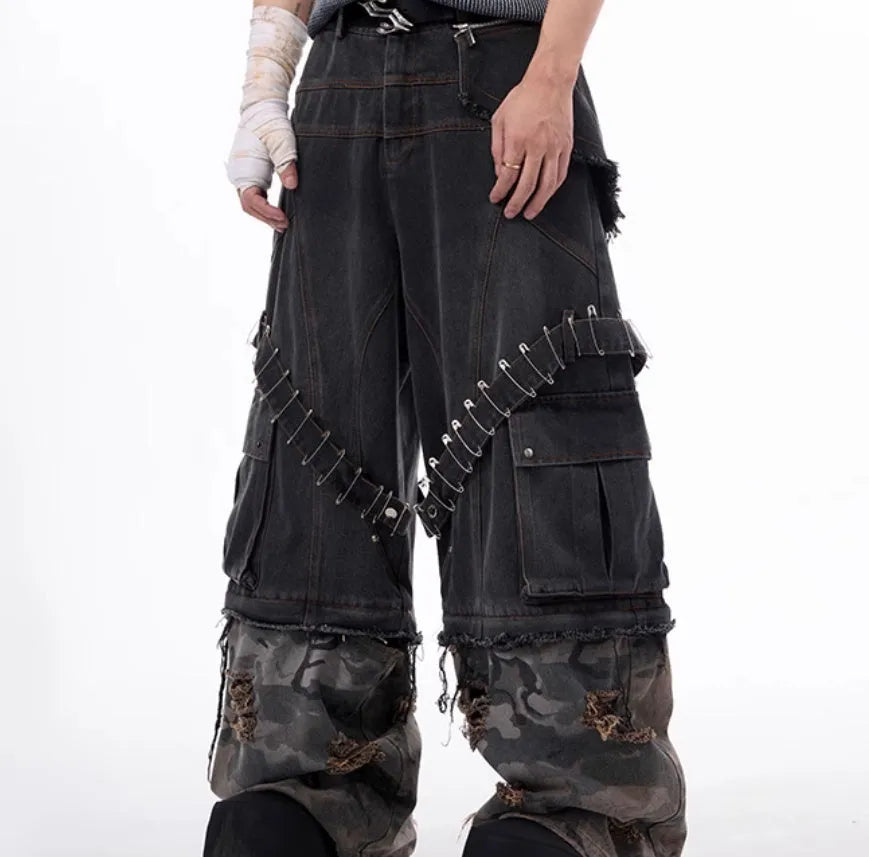 Grey men's jeans with camouflage pattern splicing and silver pin and black ribbon detailing on the legs.