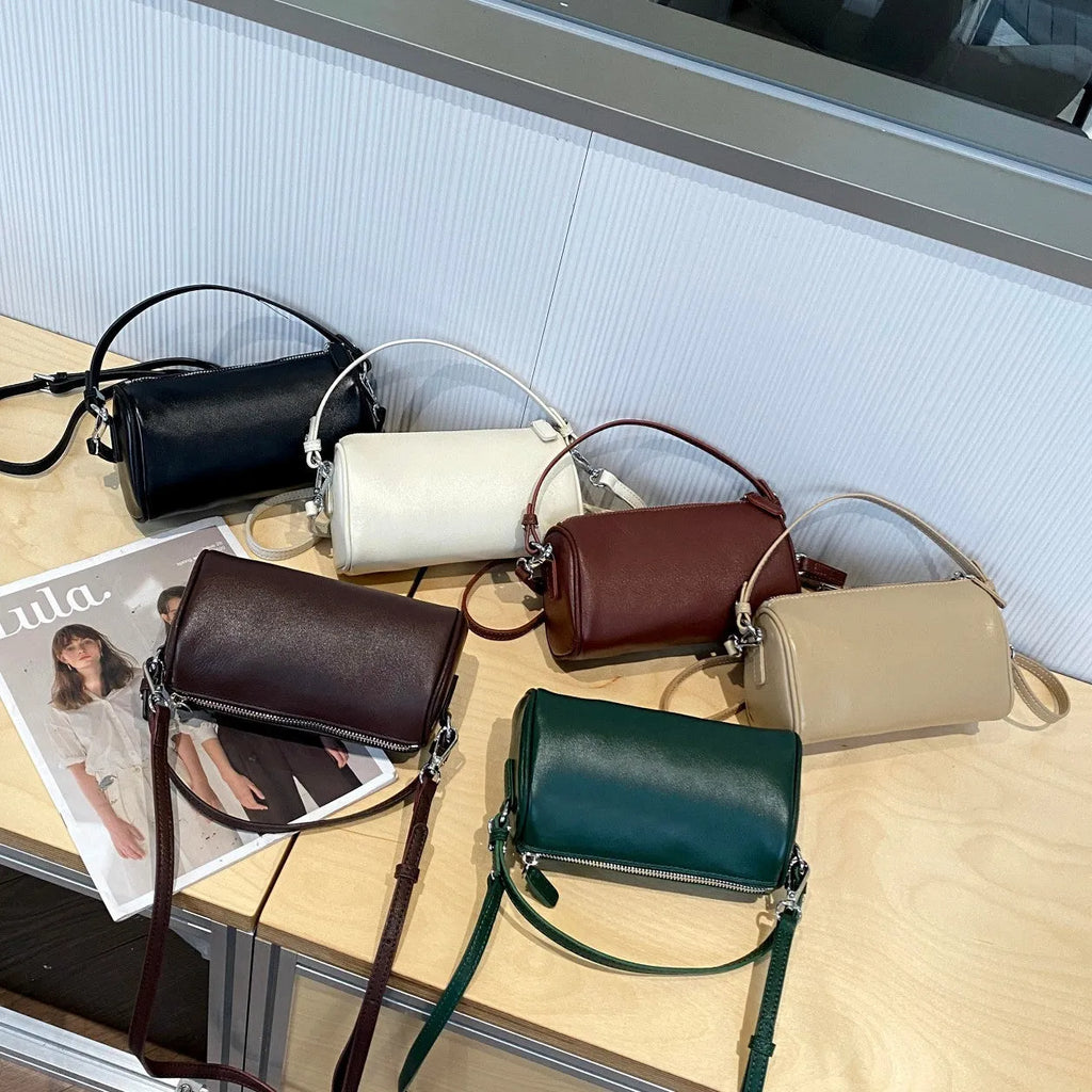 Vegetable-tanned leather cylindrical crossbody phone bag in black colour showing adjustable strap and visible stitching