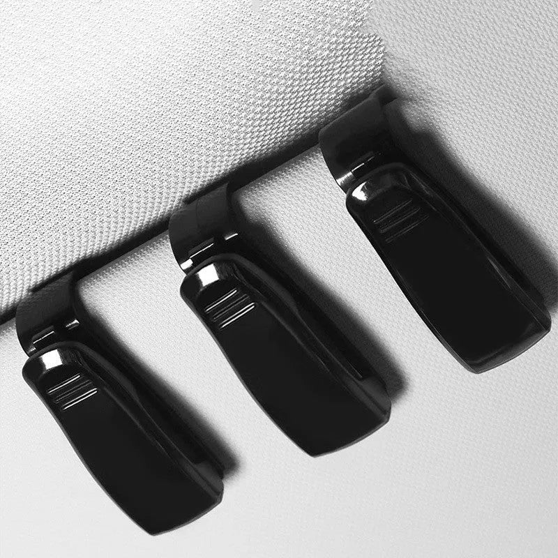 Black plastic car sun visor clip organiser for glasses and cards on a car interior.