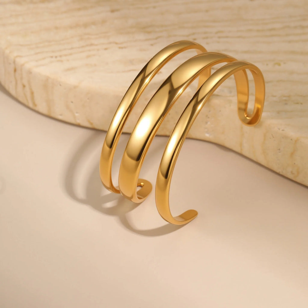 Women's stainless steel bracelet with geometric line design, shown in gold and steel finish options.
