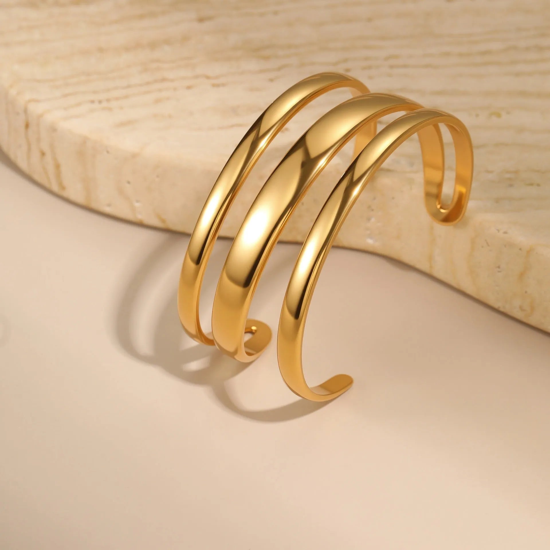Women's stainless steel bracelet with geometric line design, shown in gold and steel finish options.