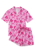 Pink women's pyjama set with bow print pattern showing top and trousers on hanger