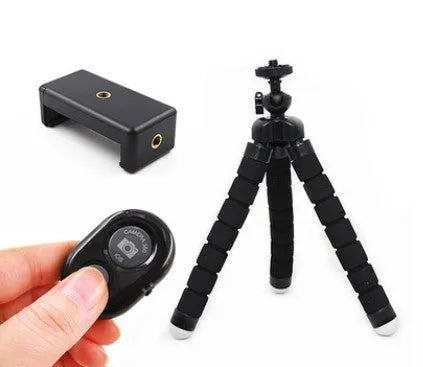 Black flexible octopus tripod with bendable legs wrapped around a pole next to a smartphone.