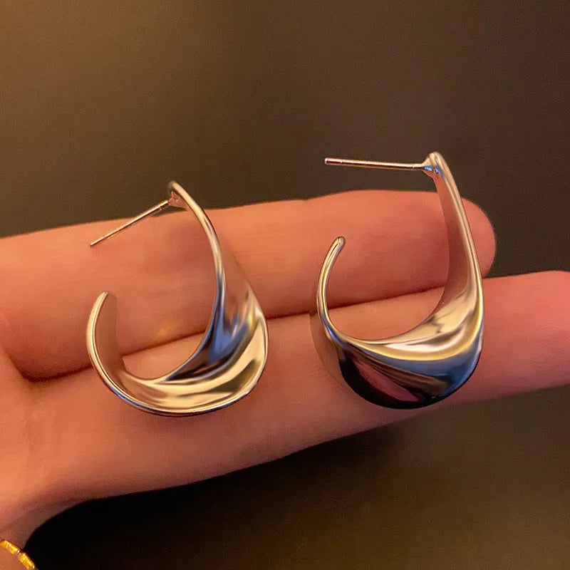 Metal twisted geometric earrings with electroplated gold or silver finish showing round design elements