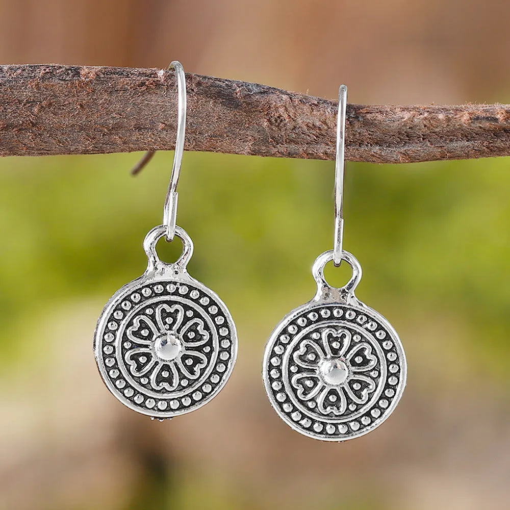 Close-up of a pair of distressed geometric bohemian earrings with a round print, in zinc alloy with electroplated colour.