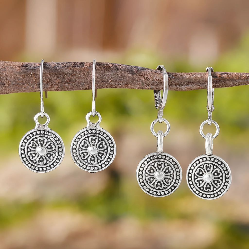 Close-up of a pair of distressed geometric bohemian earrings with a round print, in zinc alloy with electroplated colour.