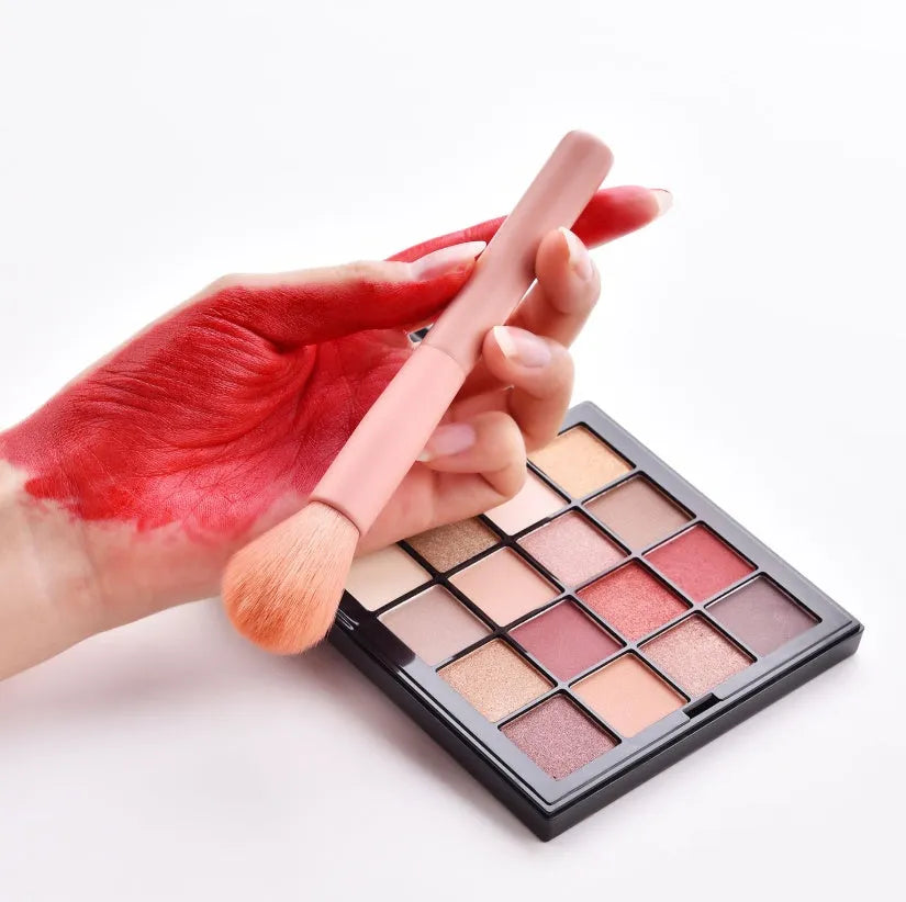 Ten professional makeup brushes with wooden handles arranged in a set, including powder, foundation and detail brushes