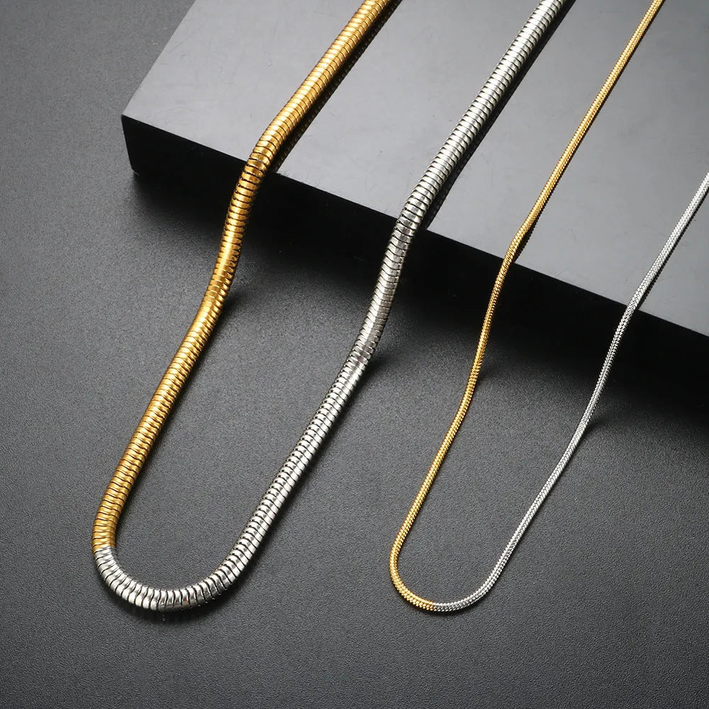 Close-up of a women's gold 3mm snake bone chain necklace with a geometric pendant.