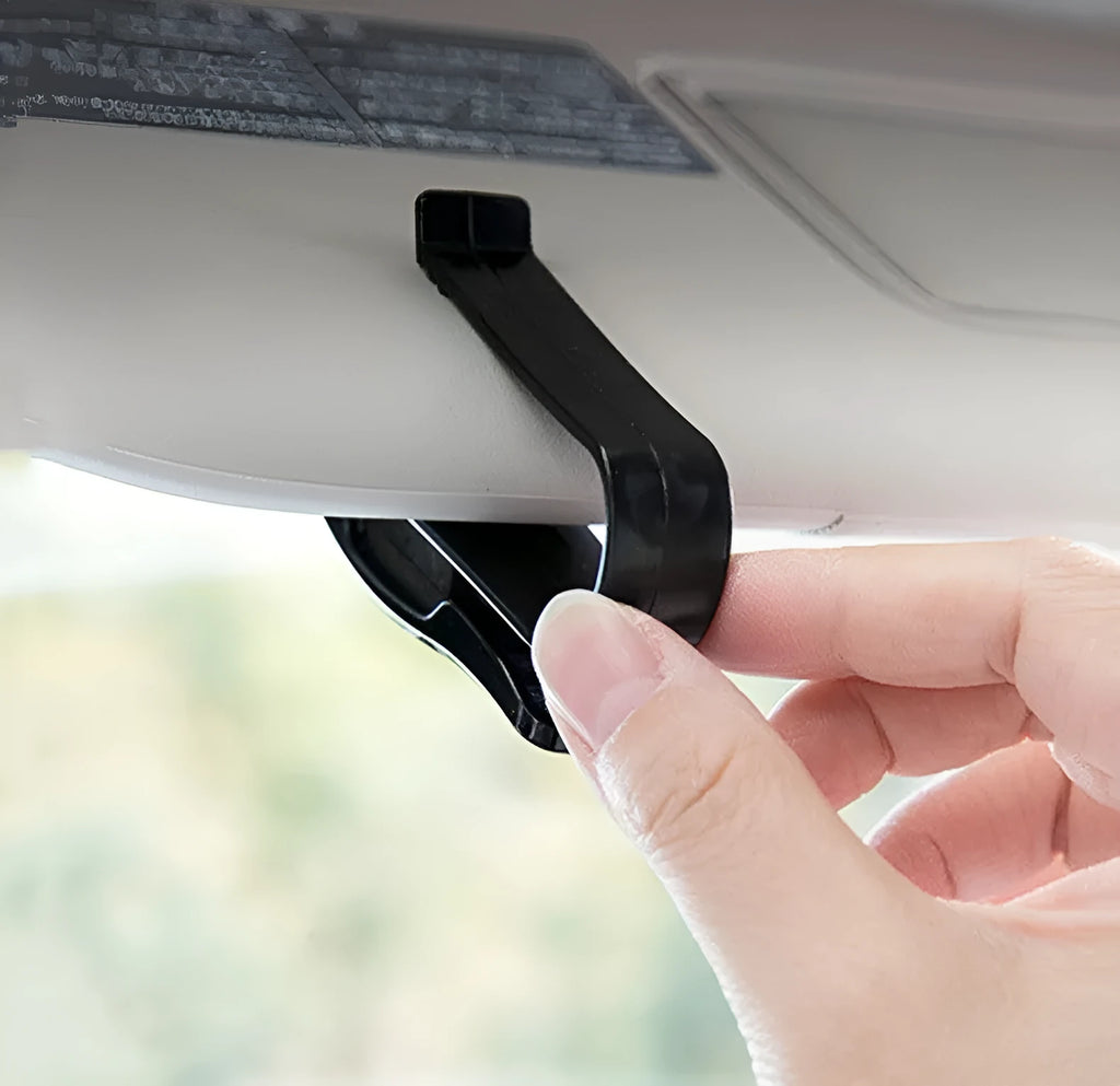 Black plastic car sun visor clip organiser for glasses and cards on a car interior.