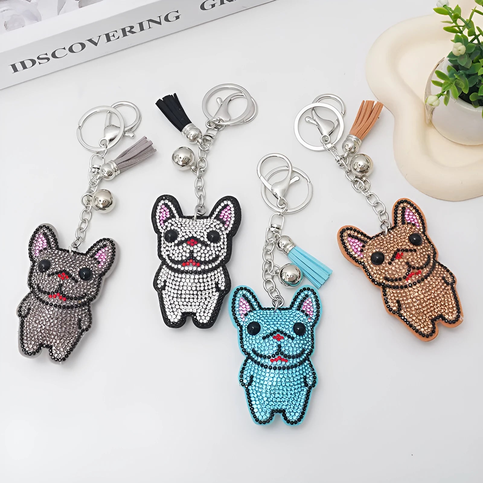 Close-up of a French dog style cartoon bear rhinestone keychain charm on a keyring.