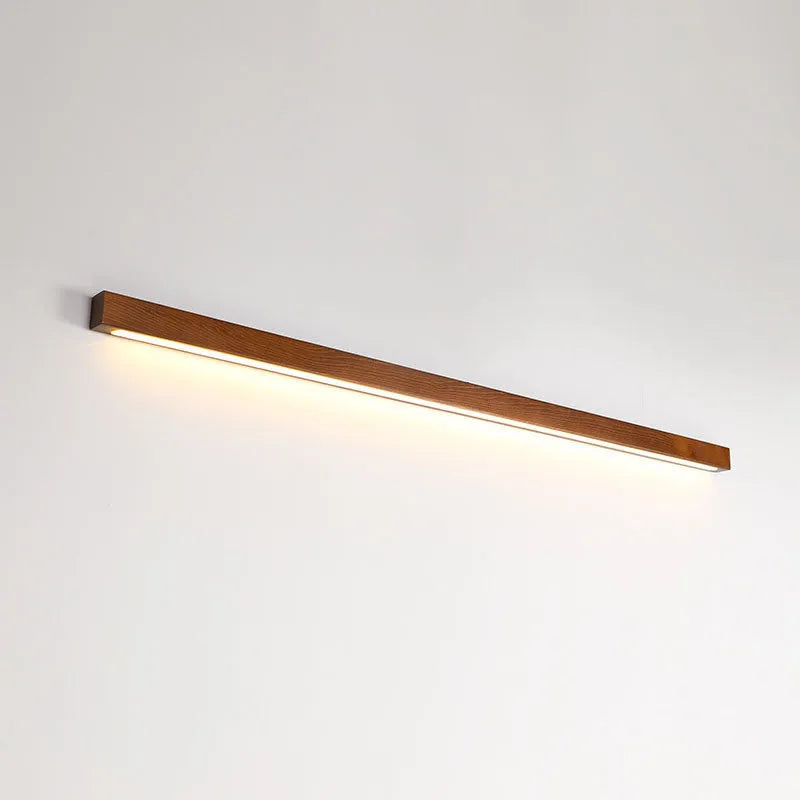 Walnut-coloured wood and acrylic minimalist LED strip wall lamp in three sizes on a white wall.