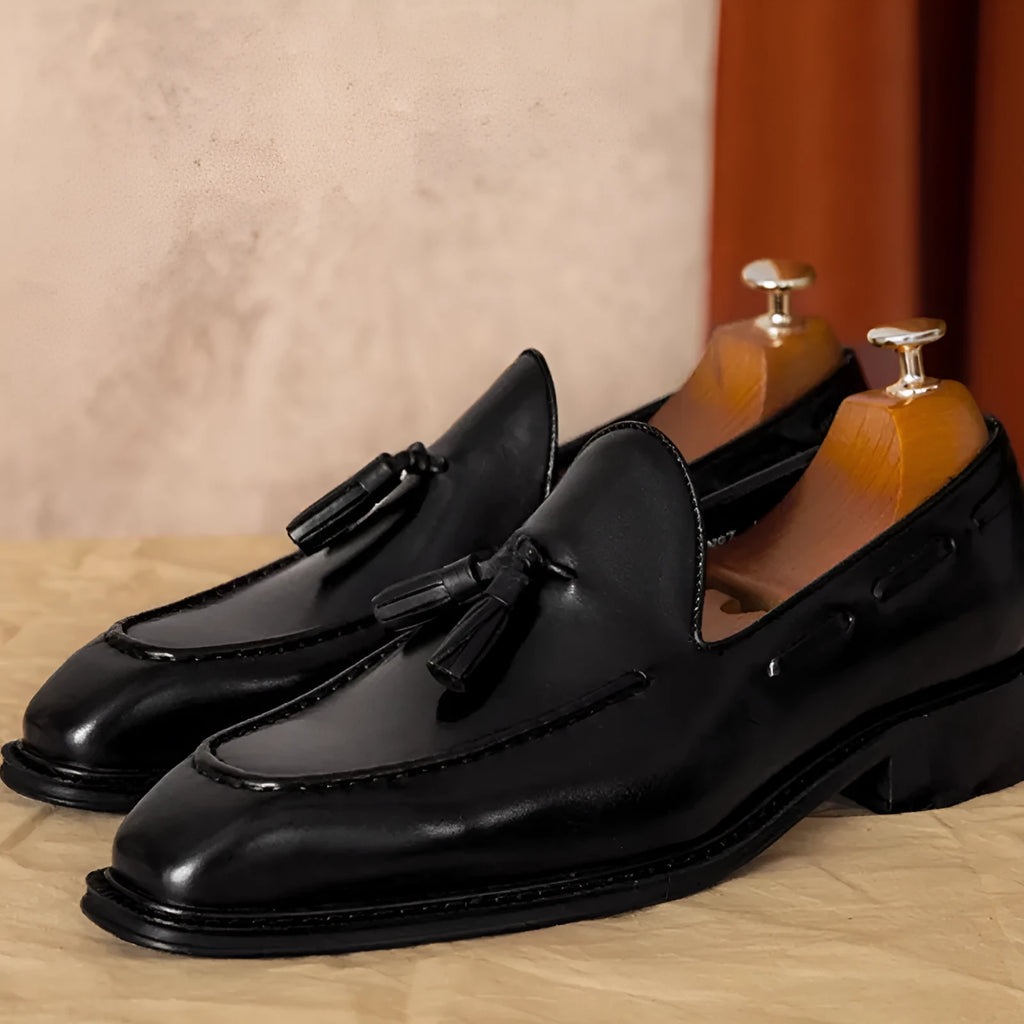 Men's black genuine leather slip-on loafers with fringed detailing on a white background