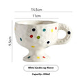A handmade, irregularly shaped ceramic mug in a solid colour, shown on a table.