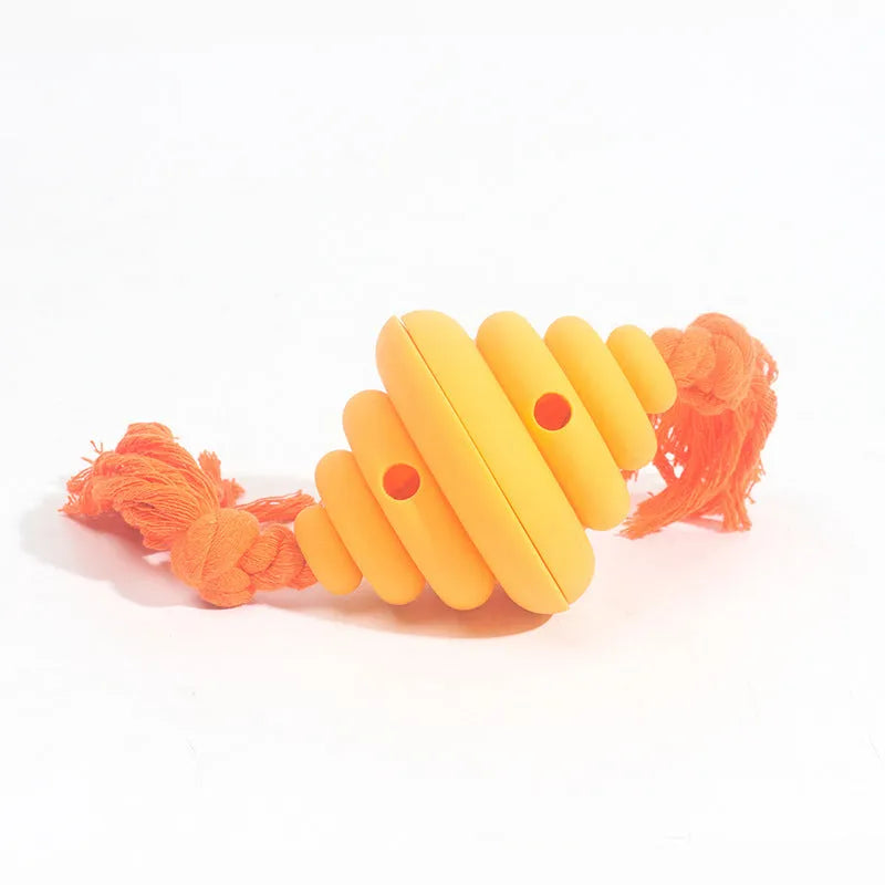 Green and yellow silicone dog ball with attached knot rope toy on grass.
