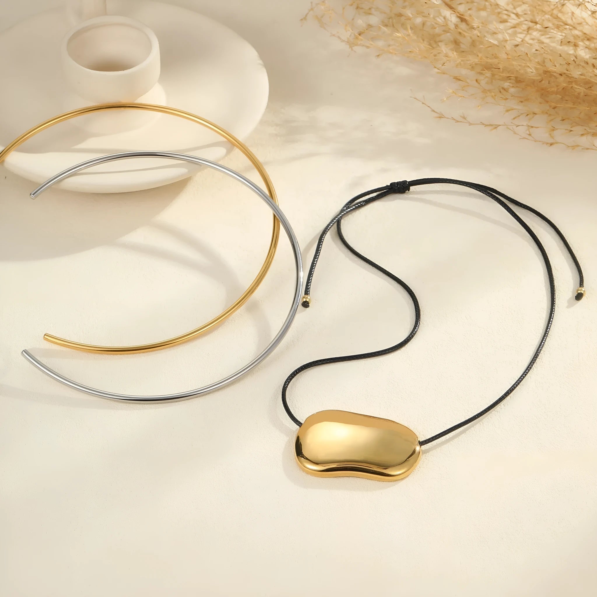 Minimalist women's stainless steel necklace with geometric pendant and matching collar chain on a dark background.