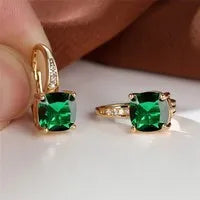 Geometric copper ear hook with round element and inlaid square zircon stone, shown in a golden colour.