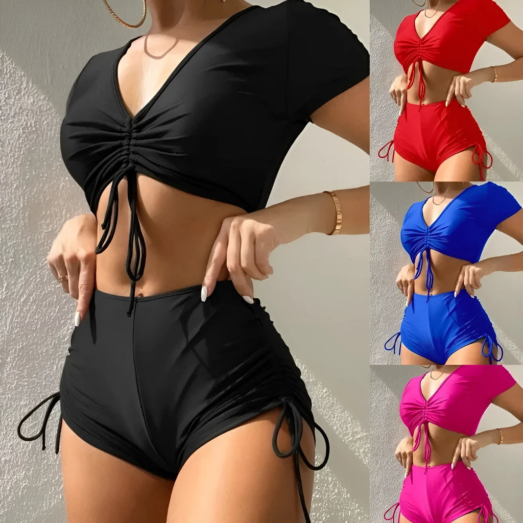 Ladies black lace-up swimsuit top with bow and matching shorts laid flat.