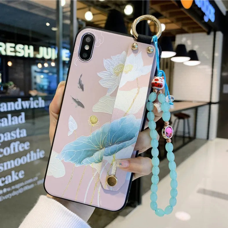 Rose flower design wrist strap attached to a phone case compatible with Apple iPhone models.