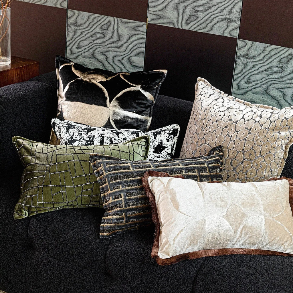 Black gold abstract patterned square decorative pillow with a soft flannel texture on a grey sofa.