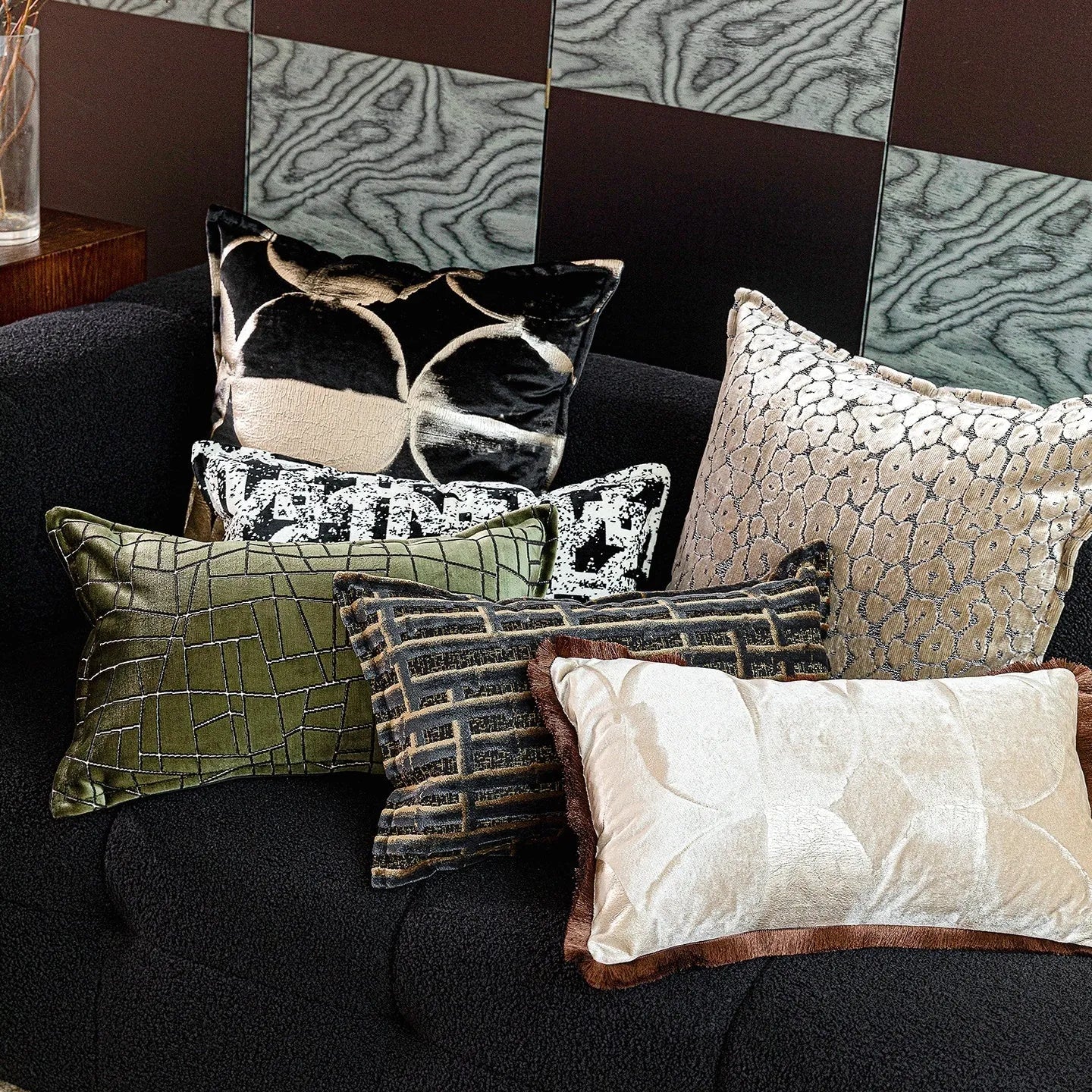 Black gold abstract patterned square decorative pillow with a soft flannel texture on a grey sofa.