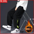 Man wearing grey green loose-fit cotton trousers with elastic ankle bands and visible stitch detailing.