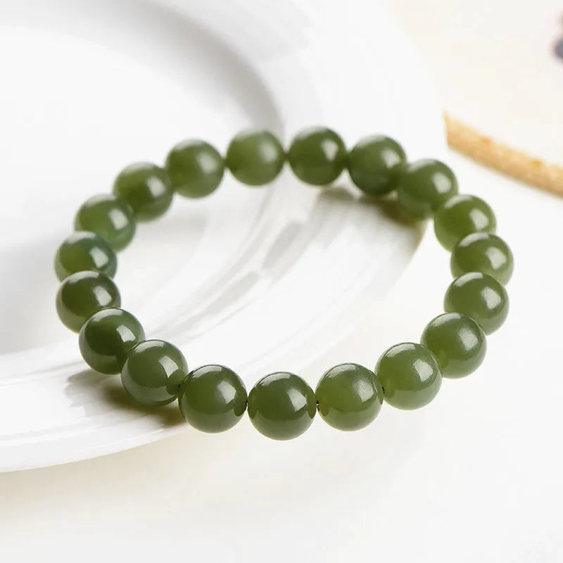 Polished Hetian Jade ball bead bracelet in deep clear water colour on a wrist.