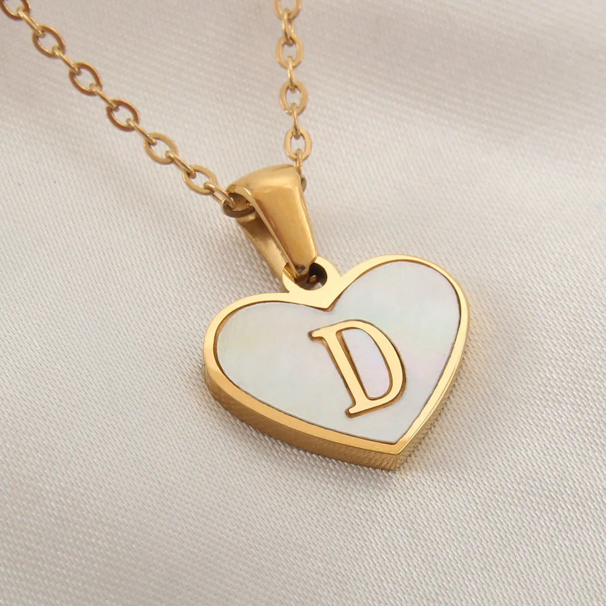 Gold chain necklace with white shell heart pendant featuring single letter customisation option