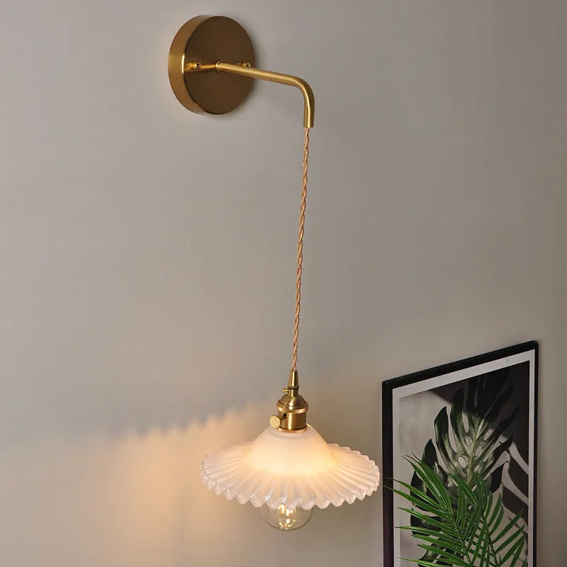Retro brass wall lamp with lotus-shaped glass shade in choice of colours, mounted on a wall.