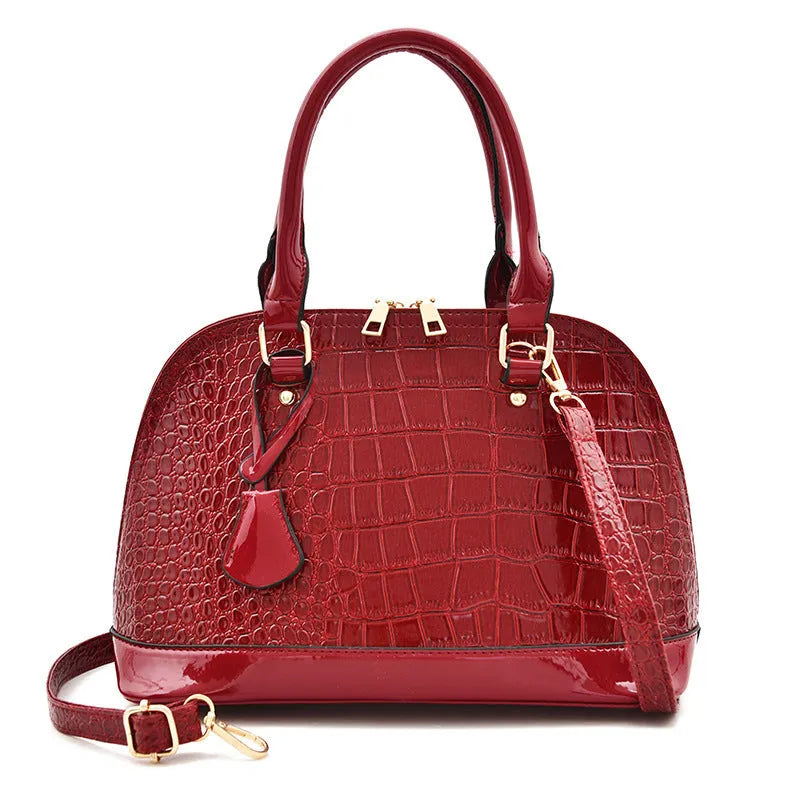 Large shiny black PU leather crossbody shoulder bag showing shell-shaped structure.