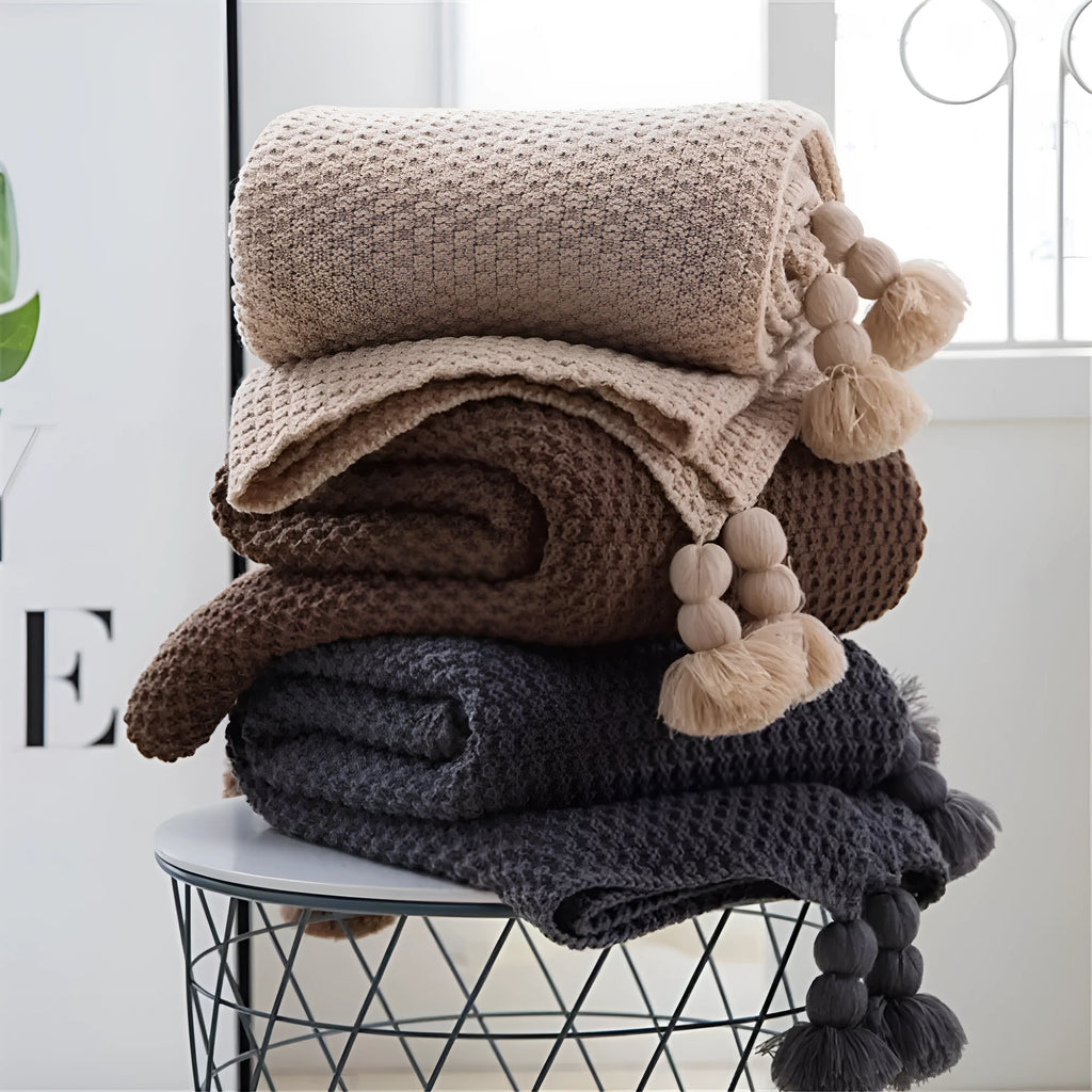 Nordic fringed knit ball acrylic blanket in beige, measuring 130 by 170 cm on a sofa.