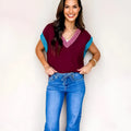 Burgundy loose V-neck sweater with contrast trim and short cuffed sleeves laid flat.