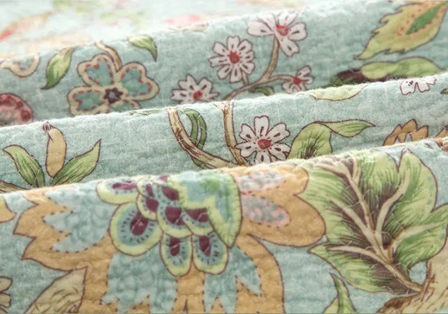 Blue cotton bedspread with floral and bird pattern, part of a 3-piece quilted bedding set.