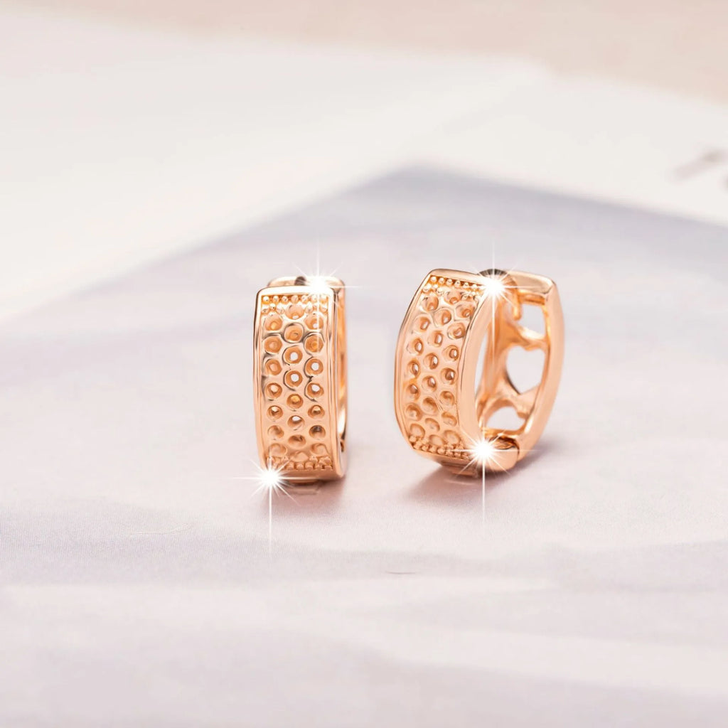 A pair of rose gold women's earrings with three hollowed-out heart shapes in a circular design.