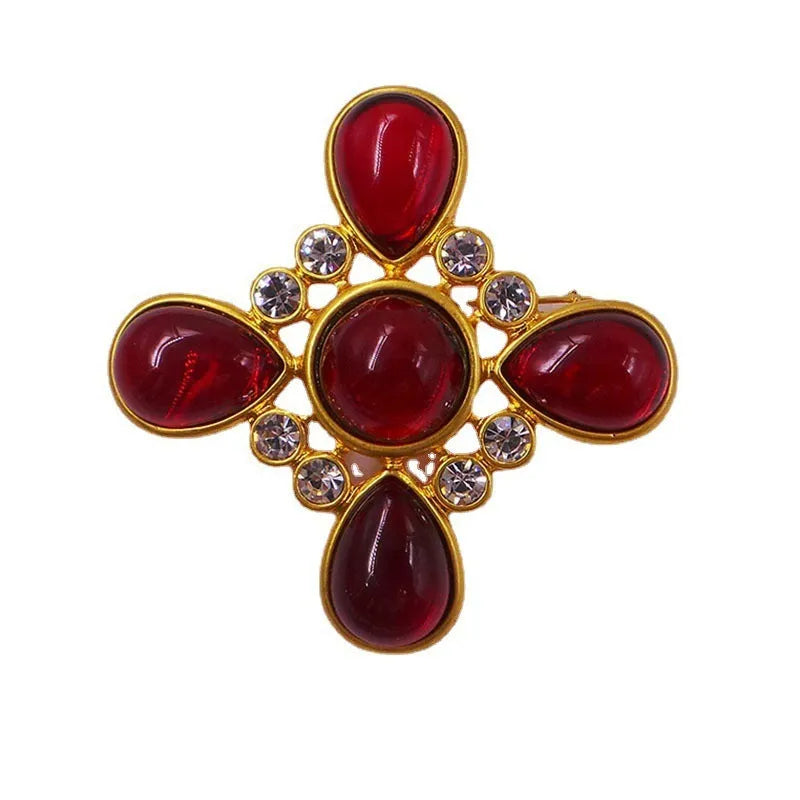 Vintage zinc alloy baroque cross brooch with crystal details on a dark fabric background.