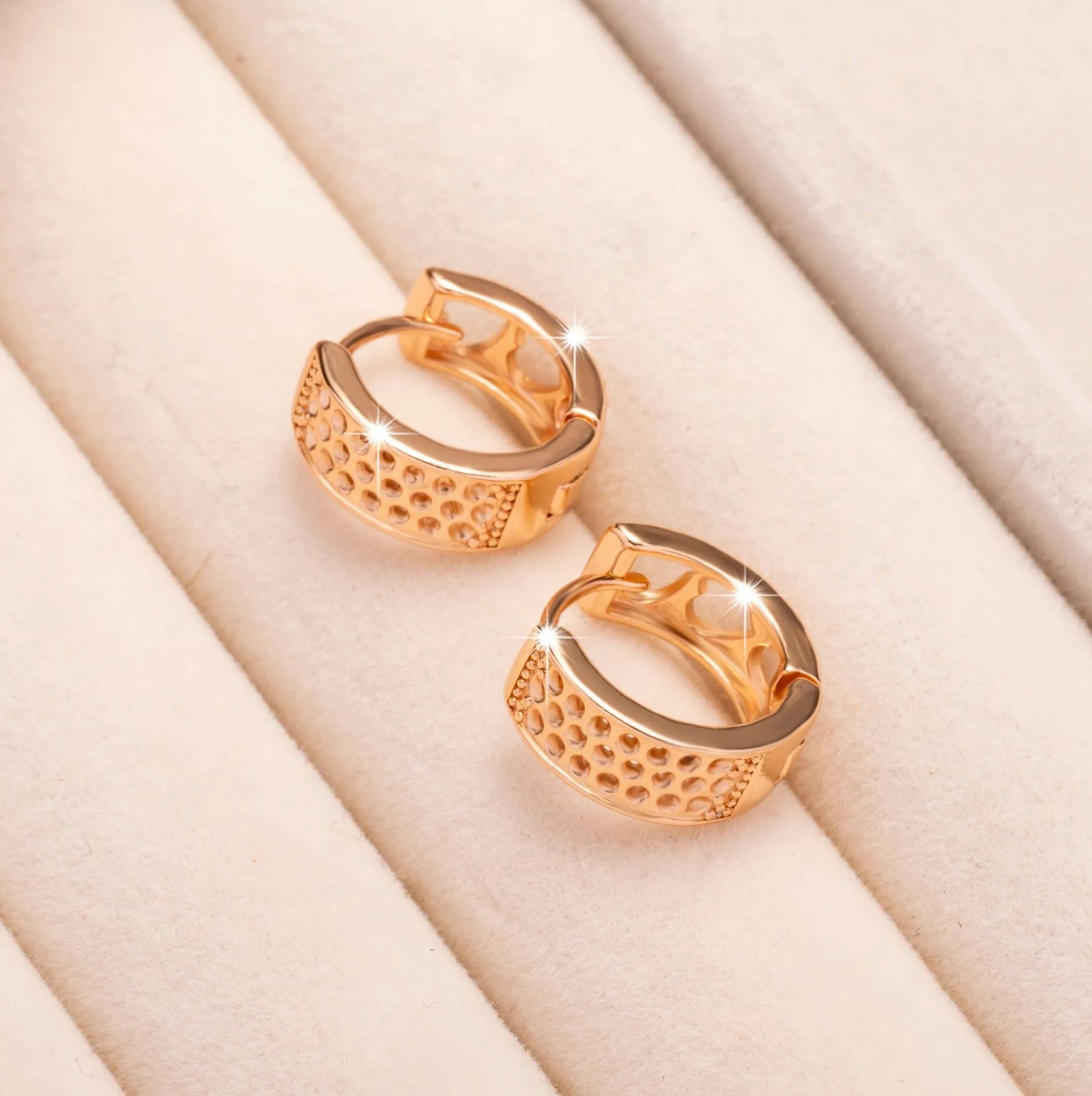 A pair of rose gold women's earrings with three hollowed-out heart shapes in a circular design.