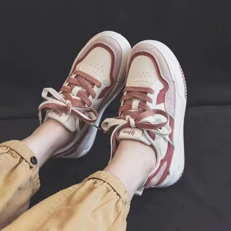 Pink and white low-top height-increasing sneakers with rubber soles on a plain background.