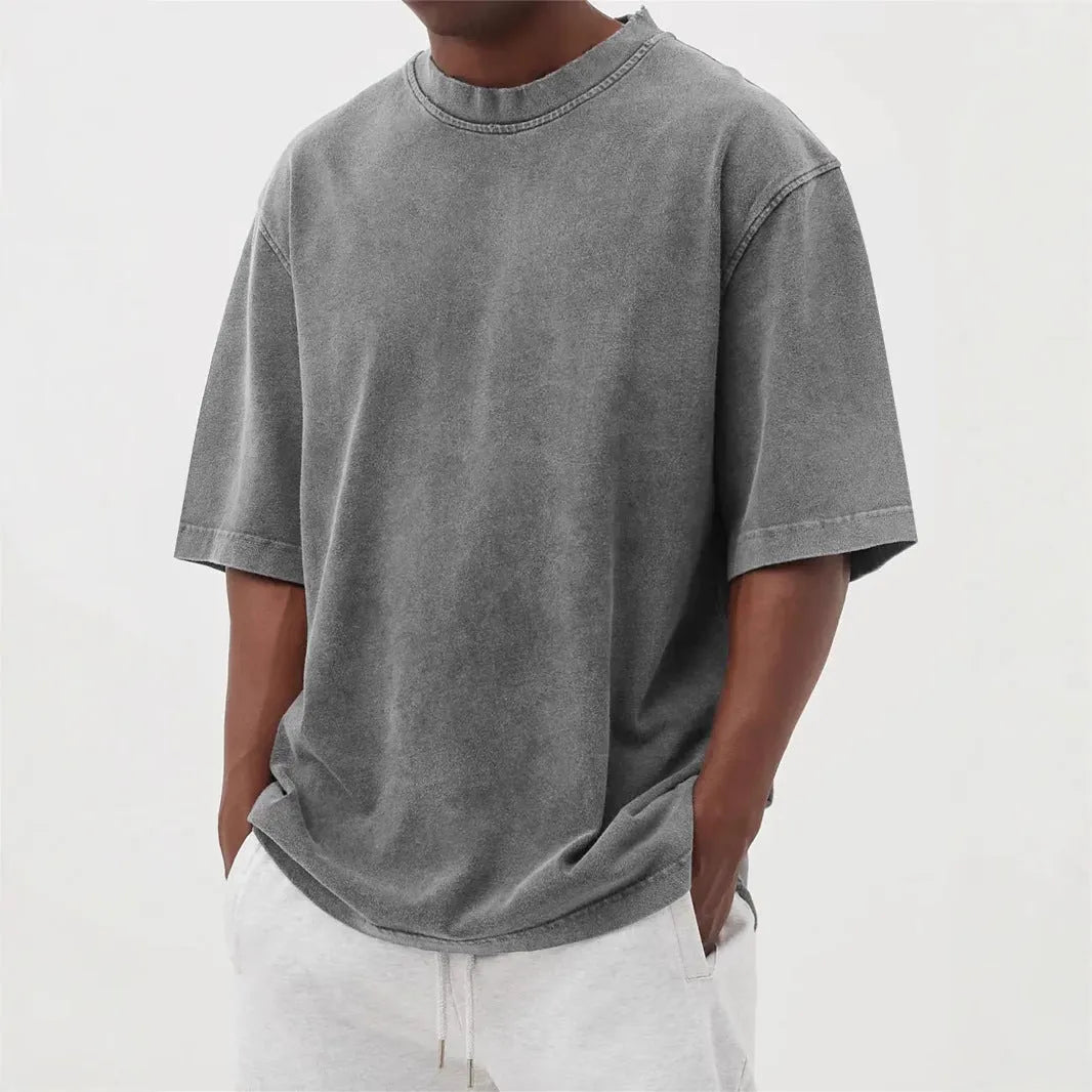 Man wearing a loose-fit distressed pullover T-shirt in a solid colour, showcasing the casual style and half-sleeve design.