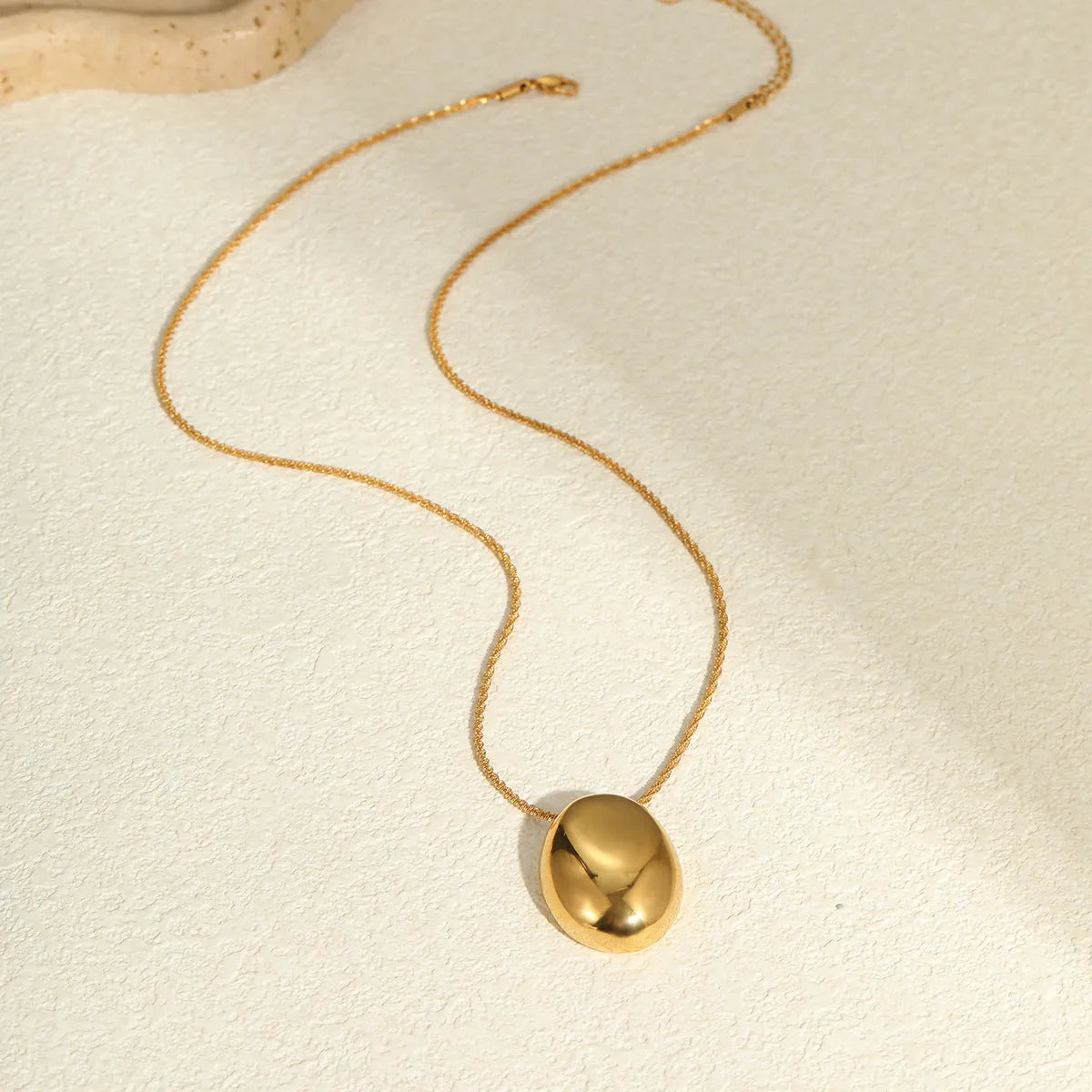 Gold geometric pendant necklace with adjustable chain on white background