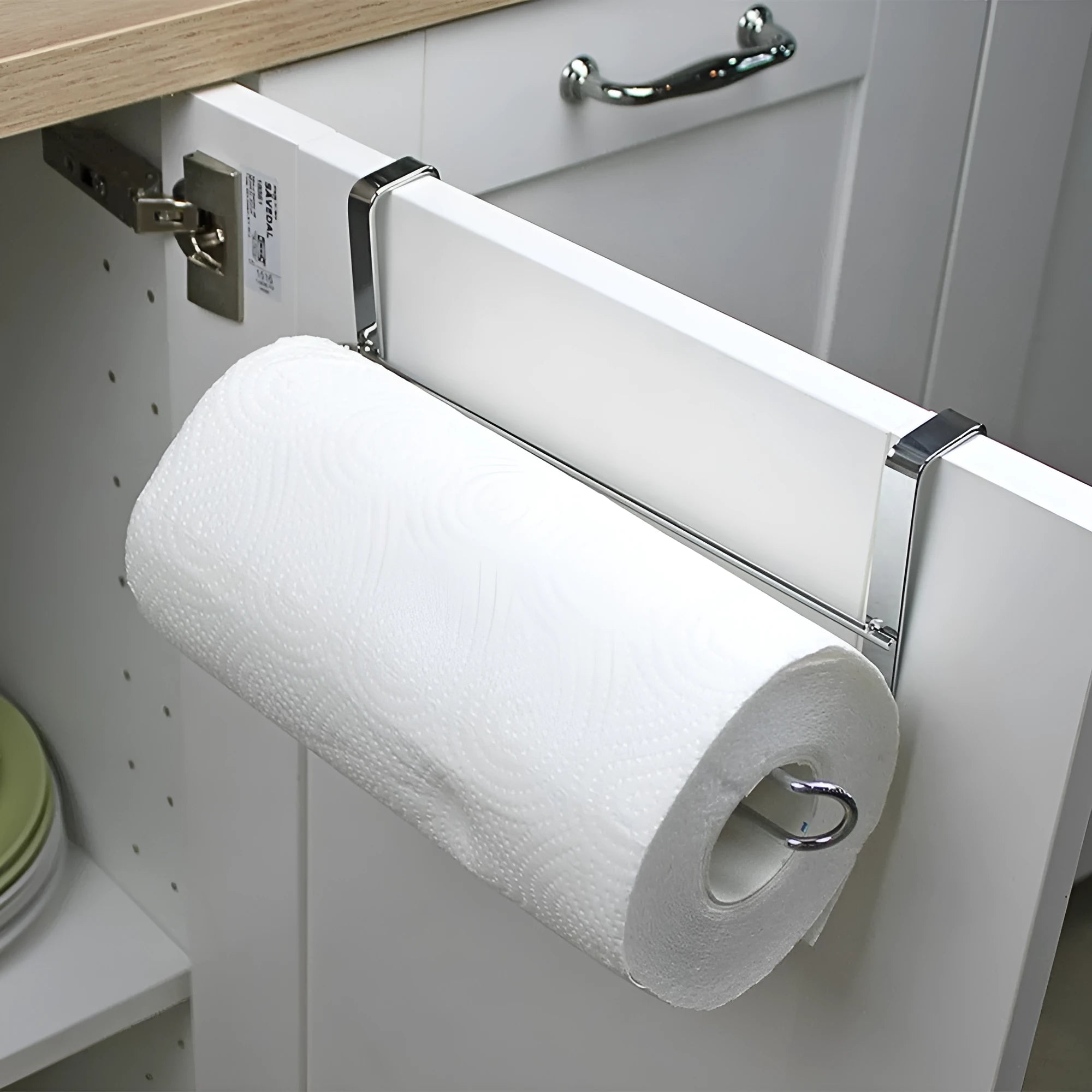 Silver stainless steel paper towel holder mounted on a kitchen cabinet door.