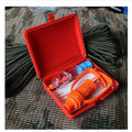 Orange portable first aid kit open, showing a venom suction pump, two suction cups, a tourniquet, and antiseptic swabs.